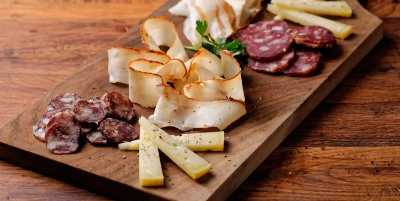 Tagliere rustico con salumi naturali, formaggio e lardo. Perfetto per abbinamenti con vini naturali.