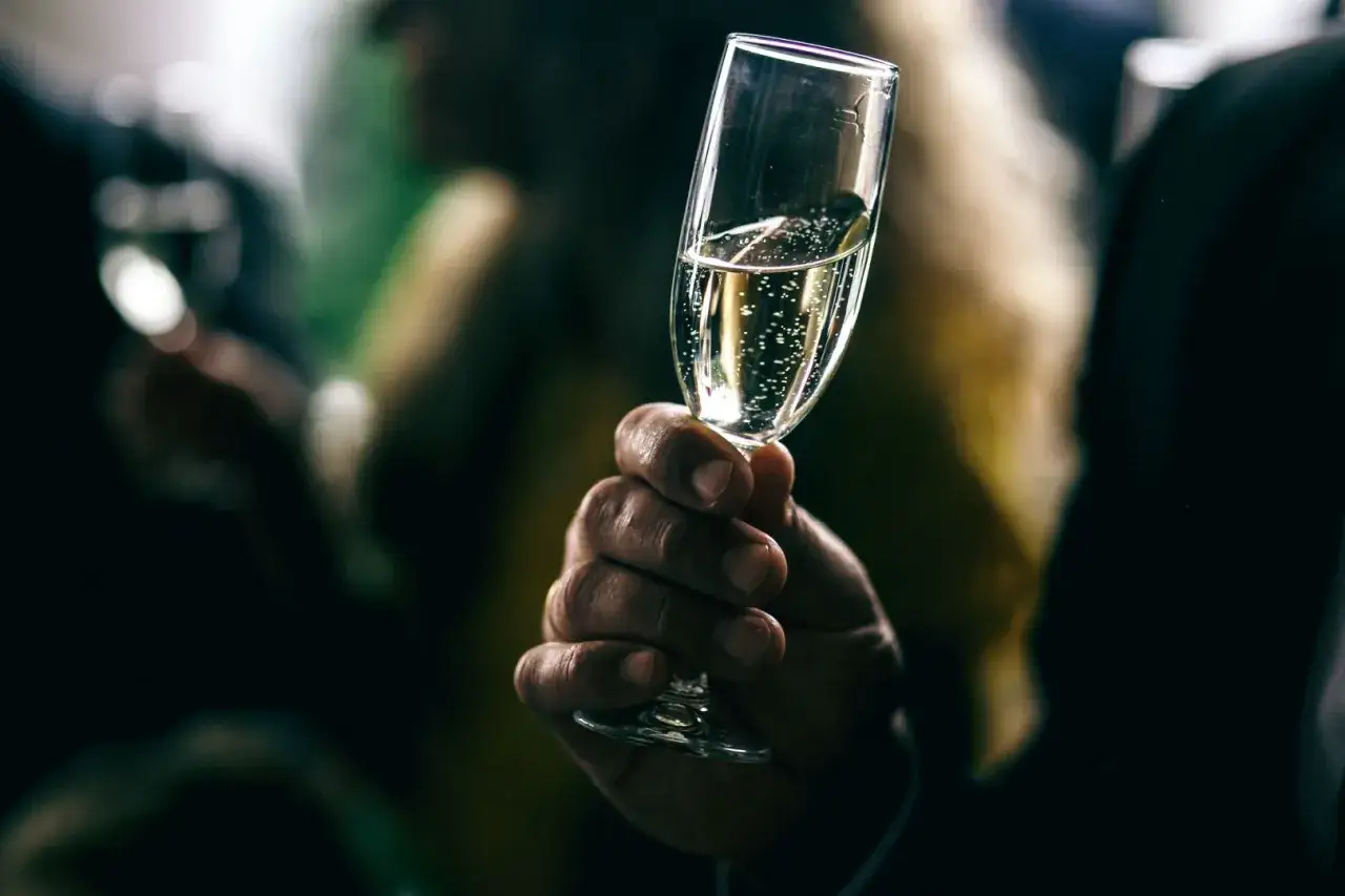 Mano che tiene un calice di spumante, il miglior spumante italiano, con bollicine scintillanti.