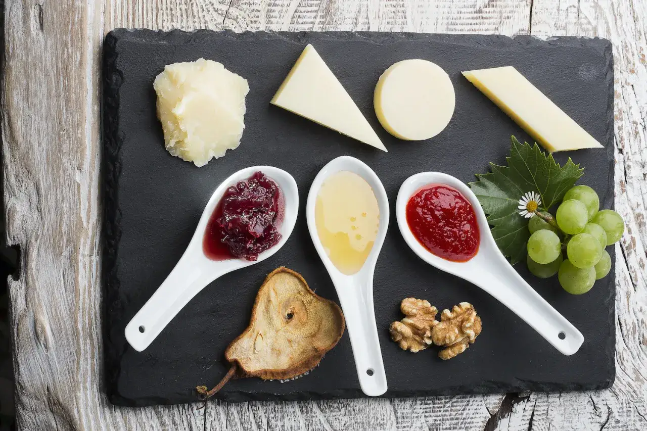 Un perfetto abbinamento formaggi marmellate e vino: degustazione con diverse varietà di formaggio, confetture, miele, frutta e noci.