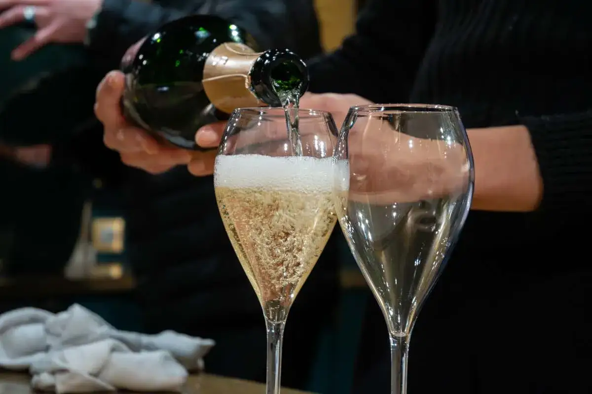 Versando spumanti italiani famosi in un calice, con un altro calice vuoto accanto. Le bollicine danzano creando un'atmosfera festosa.