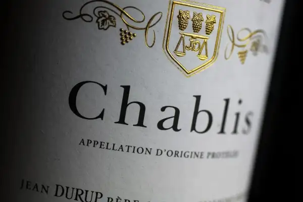 Etichetta di un vino bianco francese Chablis, con stemma dorato e grappoli d'uva.
