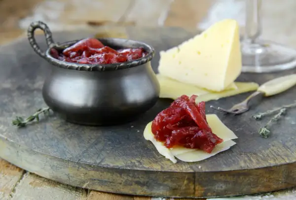 Un delizioso abbinamento formaggi marmellate e vino: formaggio stagionato con cipolle rosse caramellate, pronto per essere gustato.