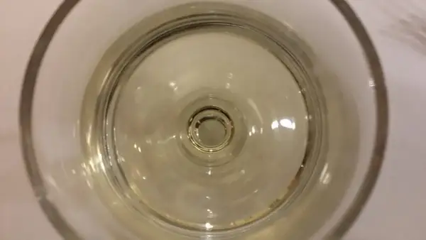 Un bicchiere di vino resinato, con riflessi dorati che danzano sul fondo.