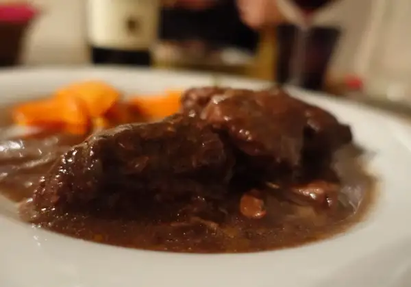 Brasato al Barolo ricetta originale piemontese: tenera carne cotta lentamente nel vino rosso, servita con carote.