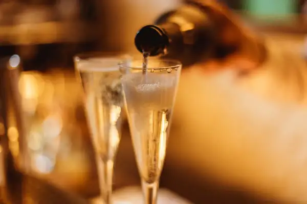 Versando vino spumante di qualità in due flute, le bollicine creano una schiuma invitante.