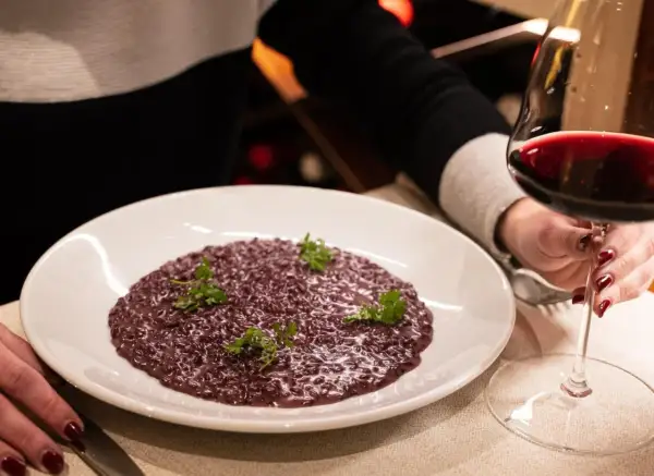 Risotto viola, perfetto abbinamento amarone. Un bicchiere di vino rosso intenso accompagna questo piatto raffinato.