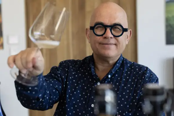 Uomo con occhiali rotondi tiene un bicchiere di champagne Francia, sorridendo.