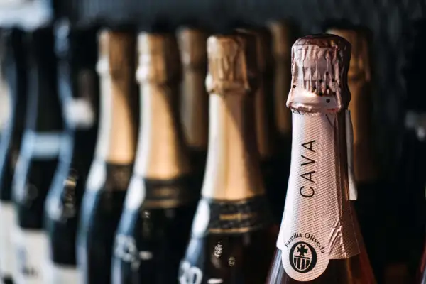 Bottiglie di cava spagnolo in fila. La bottiglia in primo piano mostra l'etichetta "CAVA Familia Oliveda".