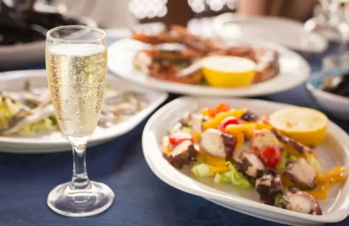 Calice di champagne con stuzzichini per aperitivo: polpo, gamberi e alici.